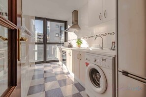 Une cuisine moderne avec un carrelage à motifs, un lave-linge encastré et une grande fenêtre.