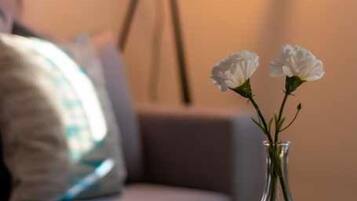 Vista clara de una habitación con una lámpara, un florero con flores y un mantel individual texturizado sobre una mesa.