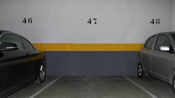 Un aparcamiento con dos coches estacionados en plazas adyacentes, identificadas con los números 46 y 47.