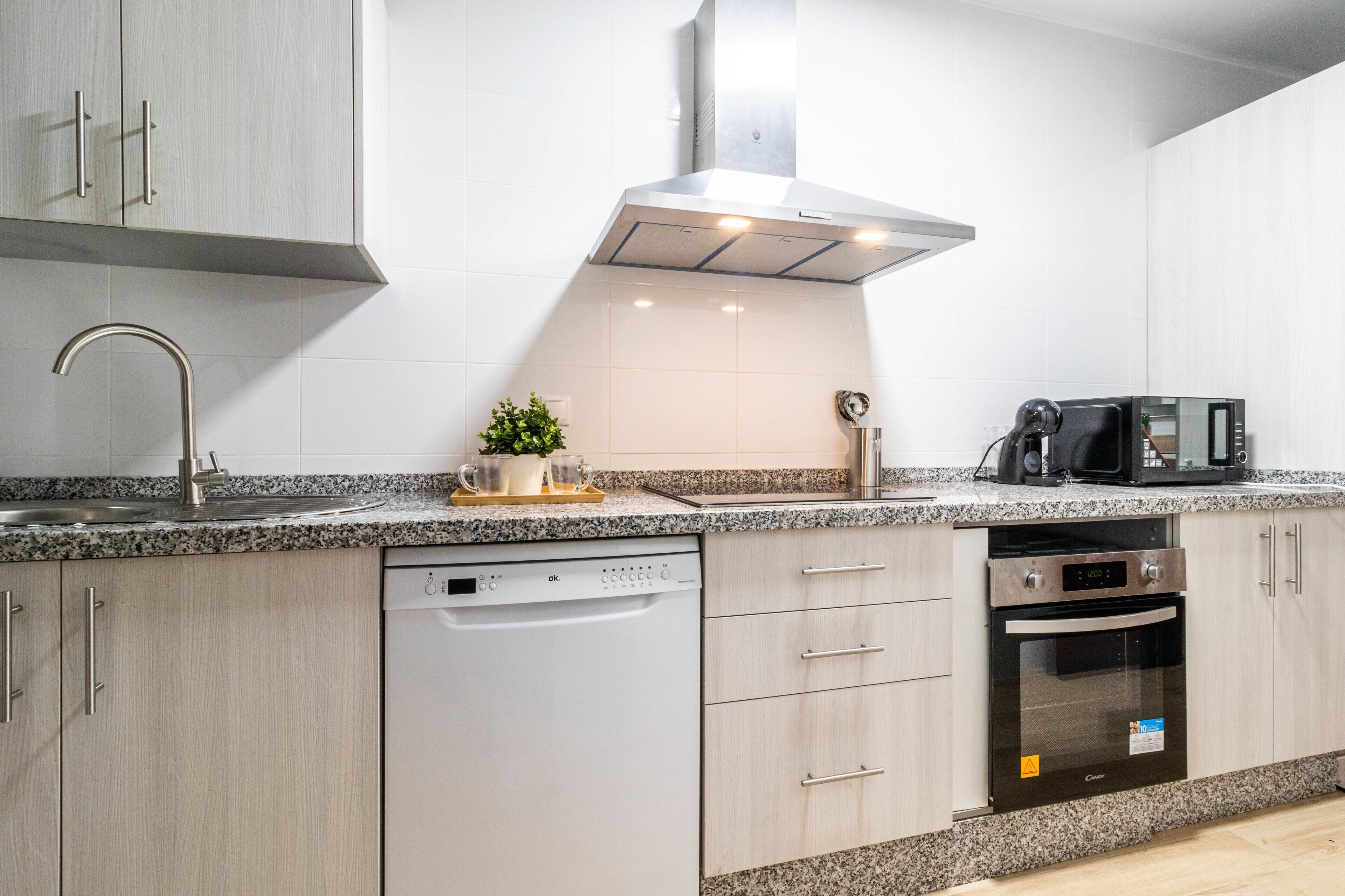 Una cocina moderna equipada con lavavajillas, horno, microondas y encimera de granito.