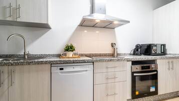 Una cocina moderna equipada con lavavajillas, horno, microondas y encimera de granito.