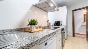 A modern kitchen with granite countertops, white cabinetry, and a built-in dishwasher. - A Estrenar Pleno Centro, Parking (Huelva)