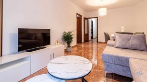 A modern living room with a flat-screen TV, a marble table, a grey sofa, and a potted plant. - A Estrenar Pleno Centro, Parking (Huelva)