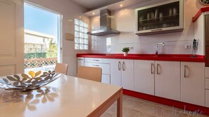 A kitchen with white cabinets, a red countertop, and a stainless steel range hood. - Chalet en la Misma Playa (Punta Umbria)