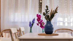 A dining table with a blue vase containing dried plants, two chairs, and a woven placemat. - Chalet a pie de Playa (Punta Umbria)