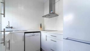 A modern kitchen with white cabinetry, a dishwasher, and a stainless steel range hood. - Chalet a pie de Playa (Punta Umbria)