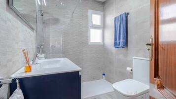 Een moderne badkamer met een bad, toilet en douche.