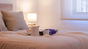 A neatly made bed with a white comforter, a white pitcher, a white cup, and a purple flower on the bed. - Chalet a pie de Playa (Punta Umbria)