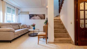 A living room with a sofa, a chair, a small table, and a staircase.