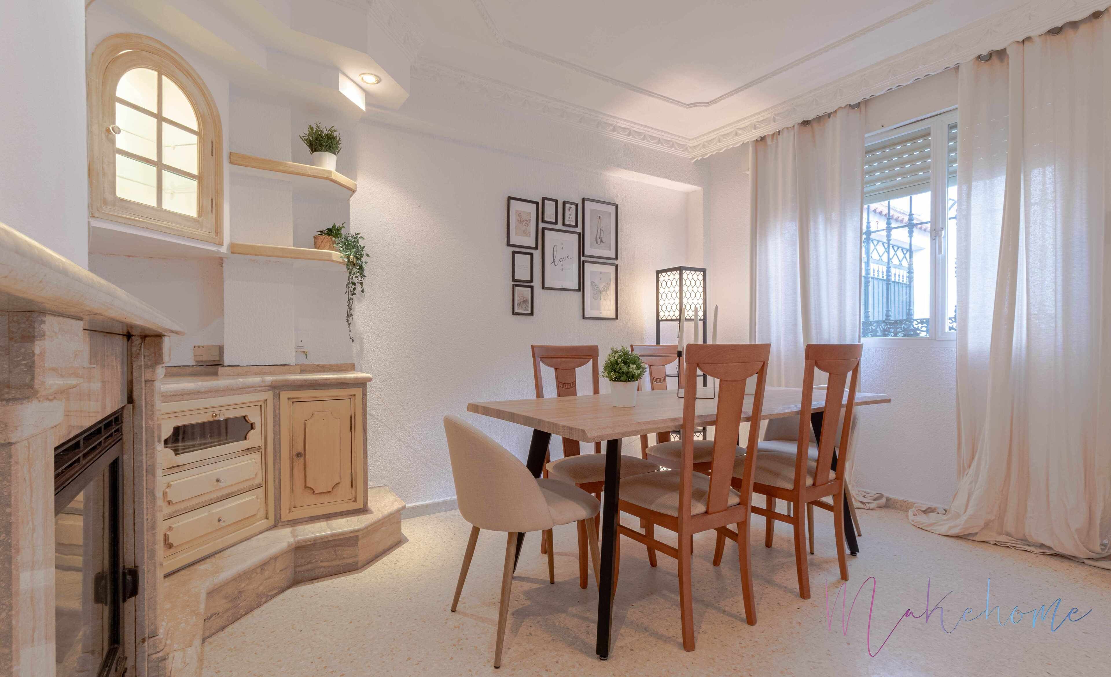 A dining area with a wooden table and chairs, a fireplace, and framed artwork on the walls.