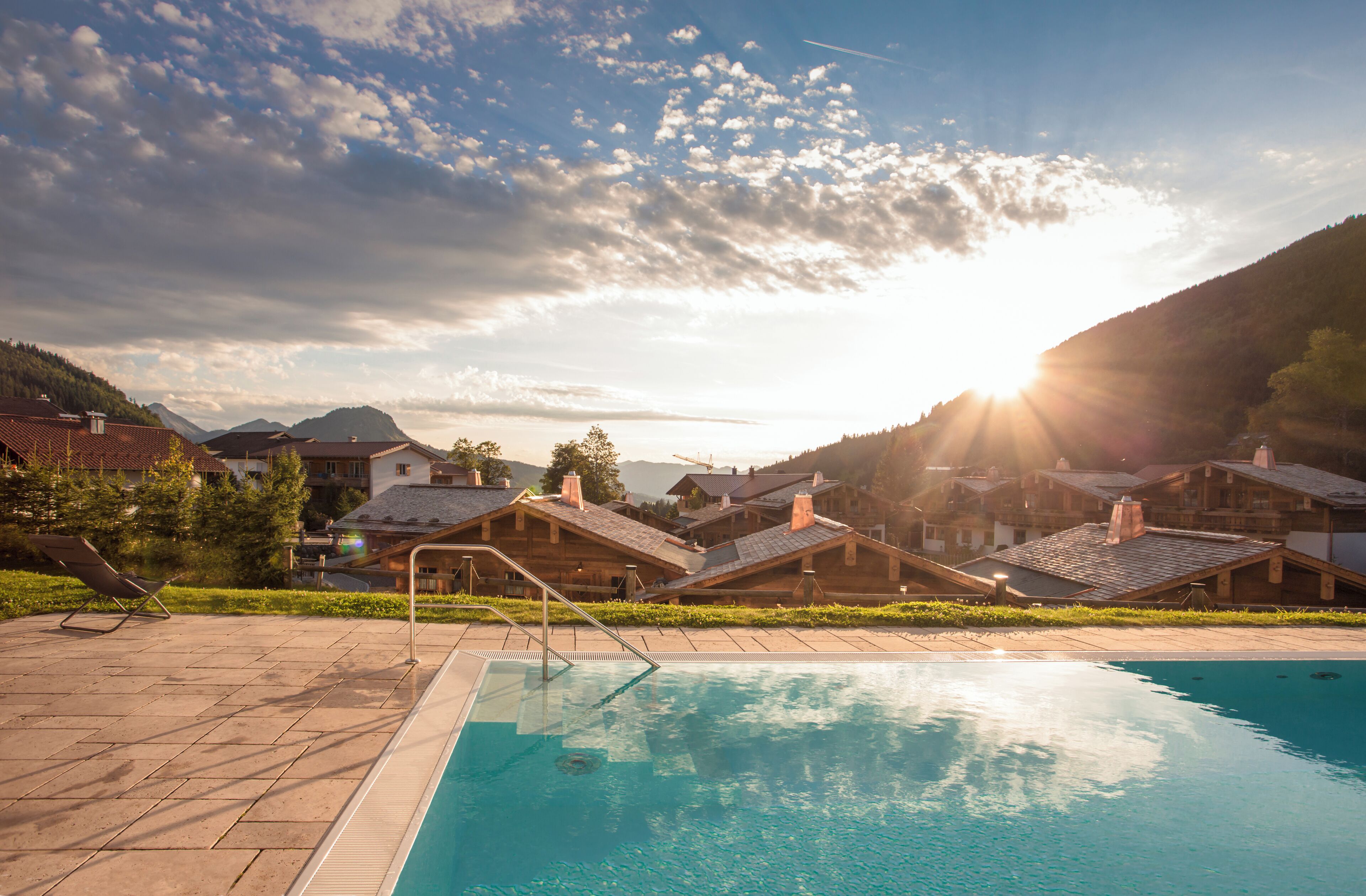 A swimming pool with a view of a mountain range and houses in the background.