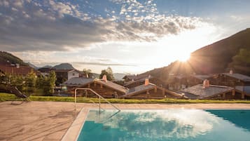 A swimming pool with a view of a mountain range and houses in the background.