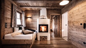 A cozy room with a fireplace, wooden walls, and a bed with a fluffy throw. - Alpin Chalets Oberjoch (Bad Hindelang)