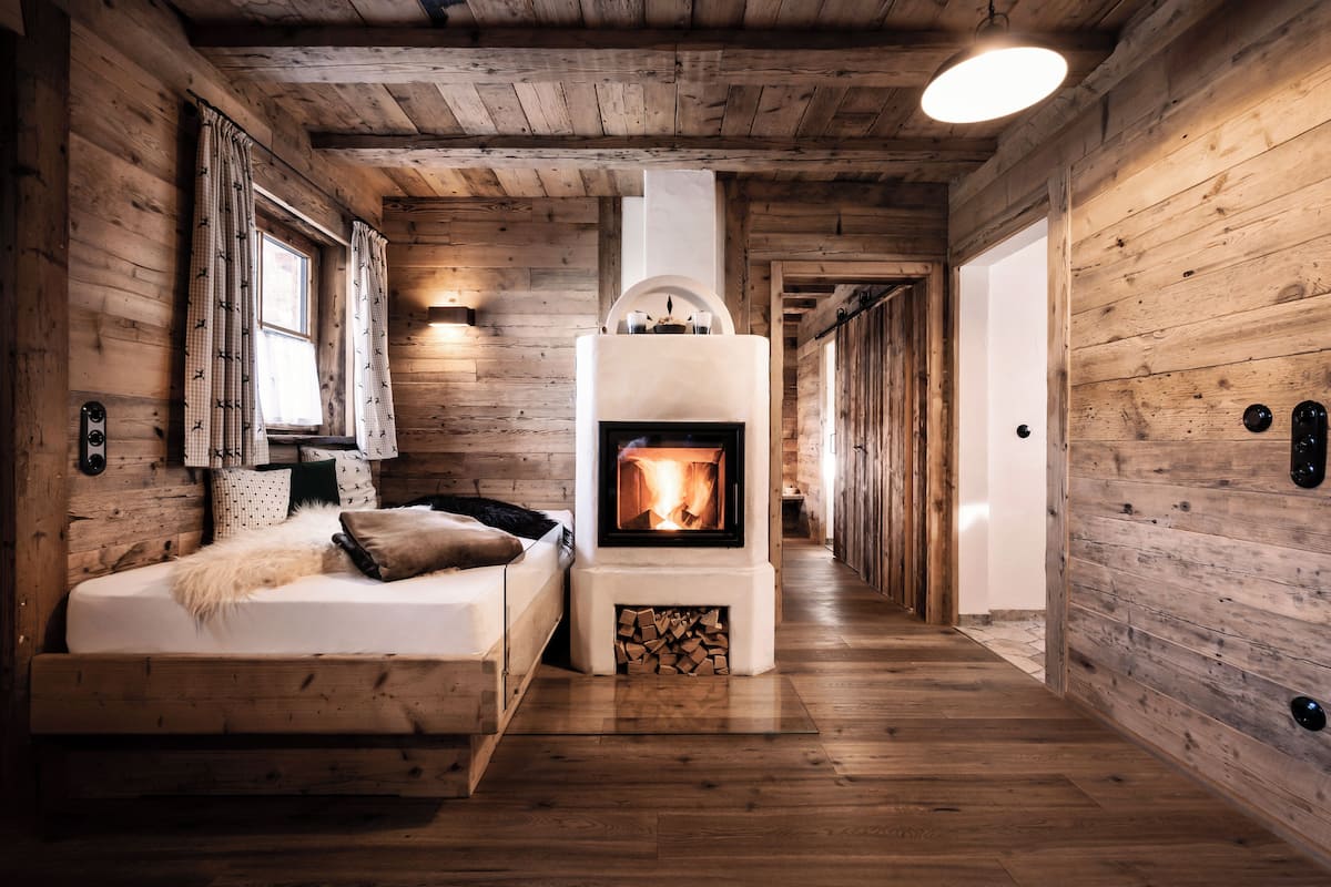 A cozy room with a fireplace, wooden walls, and a bed with a fluffy throw.