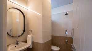 Un baño con lavamanos, espejo, inodoro y ducha.