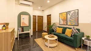 Una sala de estar moderna con un sofá verde, una mesa de centro redonda y un mostrador de recepción.