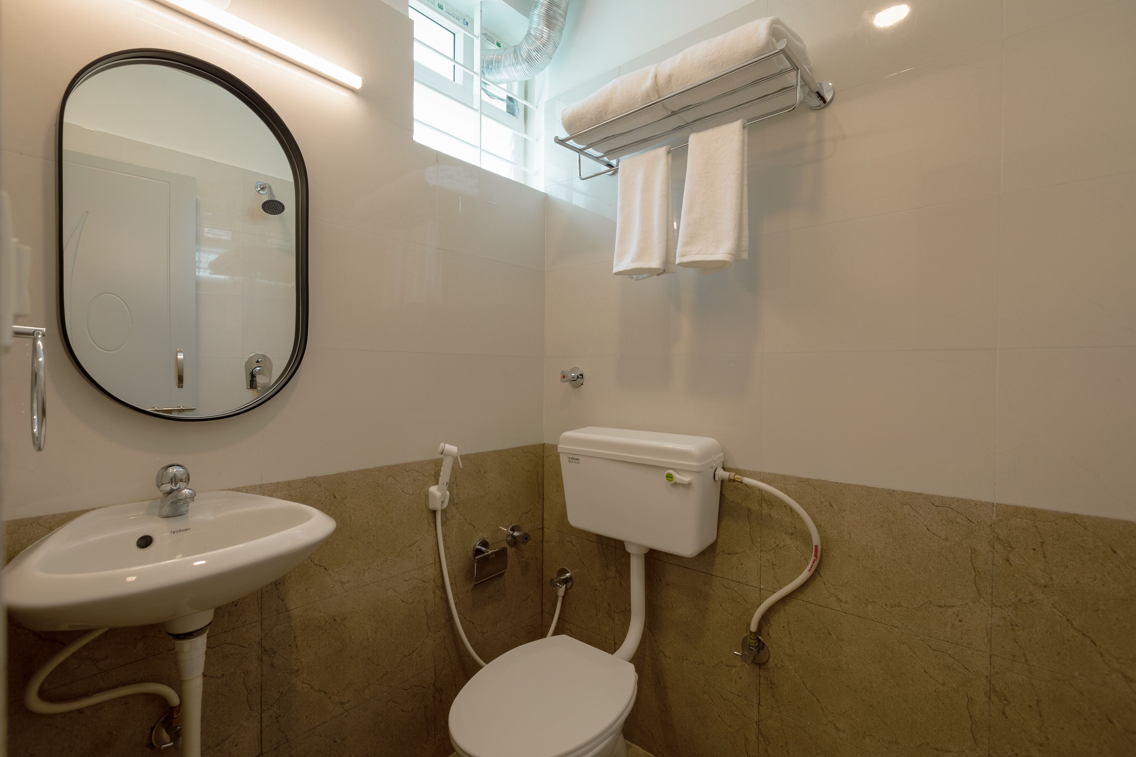 A bathroom with a white sink, a toilet, a mirror, and a towel rack.