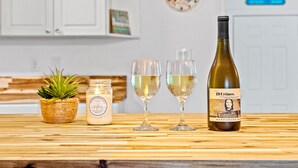 A kitchen counter with a bottle of wine, two glasses, a candle, and a small plant.