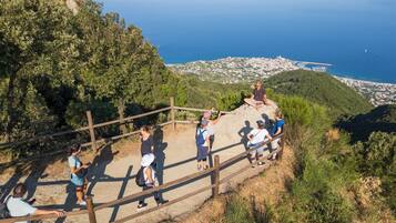 A group of people on a hiking trail with a scenic view of a coastal town and the sea in the background.