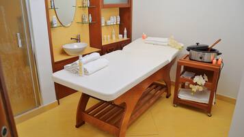 Relax in a serene space with a central treatment table, sink, and wooden shelf unit.
