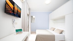 A modern hotel room with a bed, a bedside table with a tablet, a flat-screen TV on the wall, and a large mirror. - Residence Quadrifoglio (Cervia)