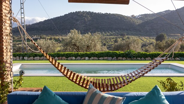 A hammock over a pool with a view of a mountainous landscape.