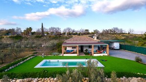 A house with a swimming pool, a covered patio, and a view of the surrounding landscape.