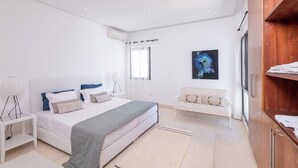 A modern bedroom with a bed, bedside tables, a bench, and a wooden cabinet. - Villa Tanit  (La Marsa)