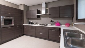 A modern kitchen with dark cabinetry, a stainless steel sink, and a range hood. - Villa Tanit  (La Marsa)