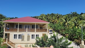 A two-story building with a red roof, multiple windows, and a balcony. - New construction spacious villa with beautiful sunset view quick ride to beach!  (Fountain, Saint Vincent and The Grenadines)