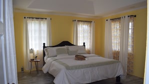 A bedroom with a bed, curtains, a bedside table, and a lamp. - New construction spacious villa with beautiful sunset view quick ride to beach!  (Fountain, Saint Vincent and The Grenadines)
