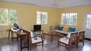 A living room with a wooden dining table, two sofas, and a TV. - New construction spacious villa with beautiful sunset view quick ride to beach!  (Fountain, Saint Vincent and The Grenadines)