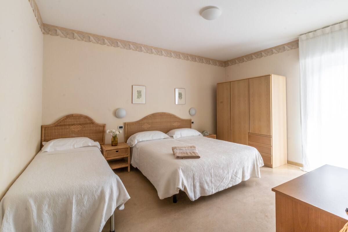 Une chambre d’hôtel avec deux lits simples, une armoire en bois et un bureau.