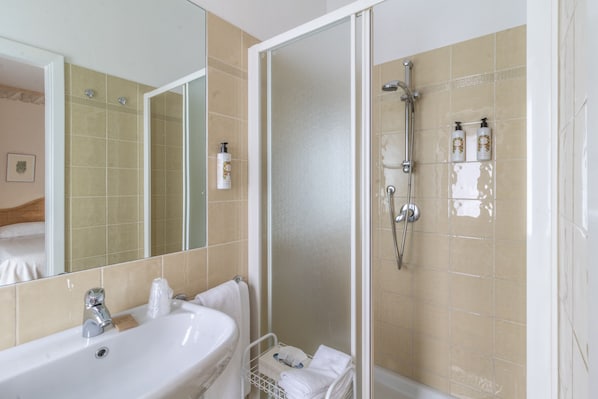 A bathroom with a sink, mirror, shower, and toiletries. - Villa Arizona B&B (Cervia)