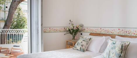 A bedroom with two beds, a nightstand, a vase with flowers, and a balcony with a chair.