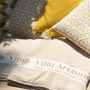 A bed with a beige blanket labeled "Villa Arizona B&B - Milano Marittima." - Villa Arizona B&B (Cervia)