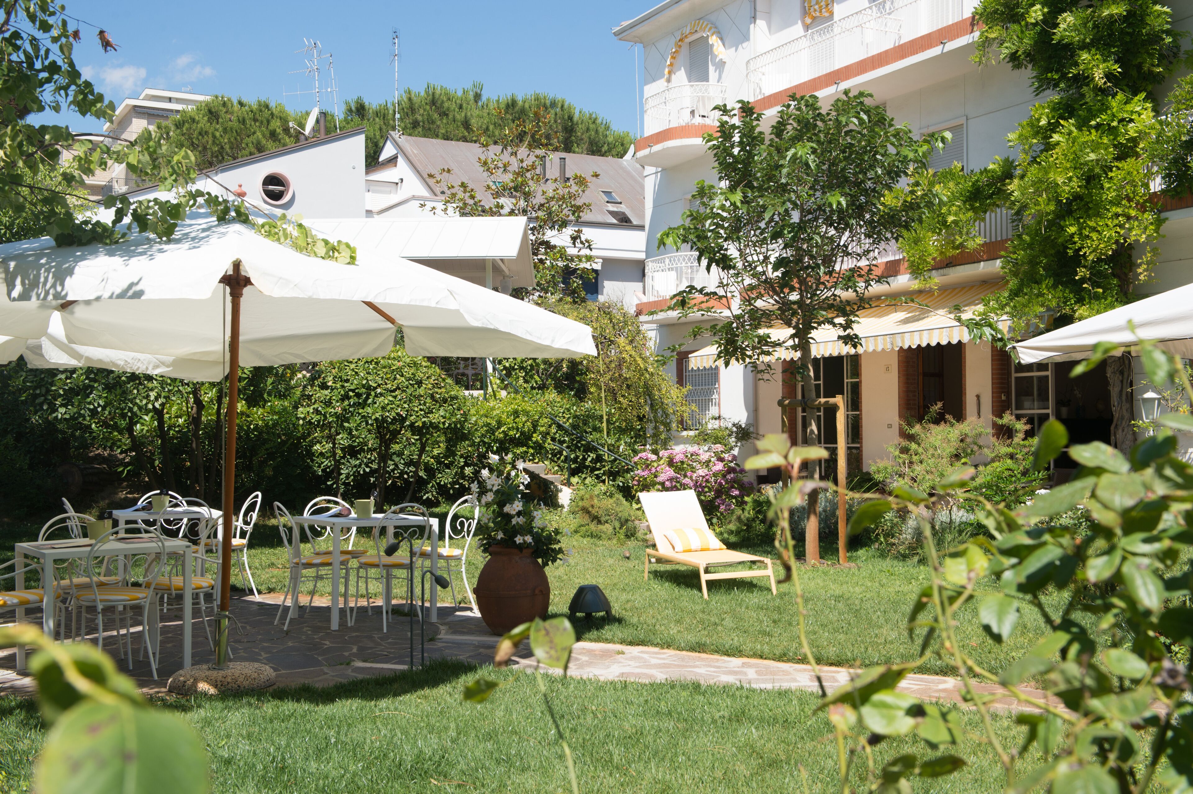 A courtyard with outdoor seating, a lounge chair, and a large umbrella.
