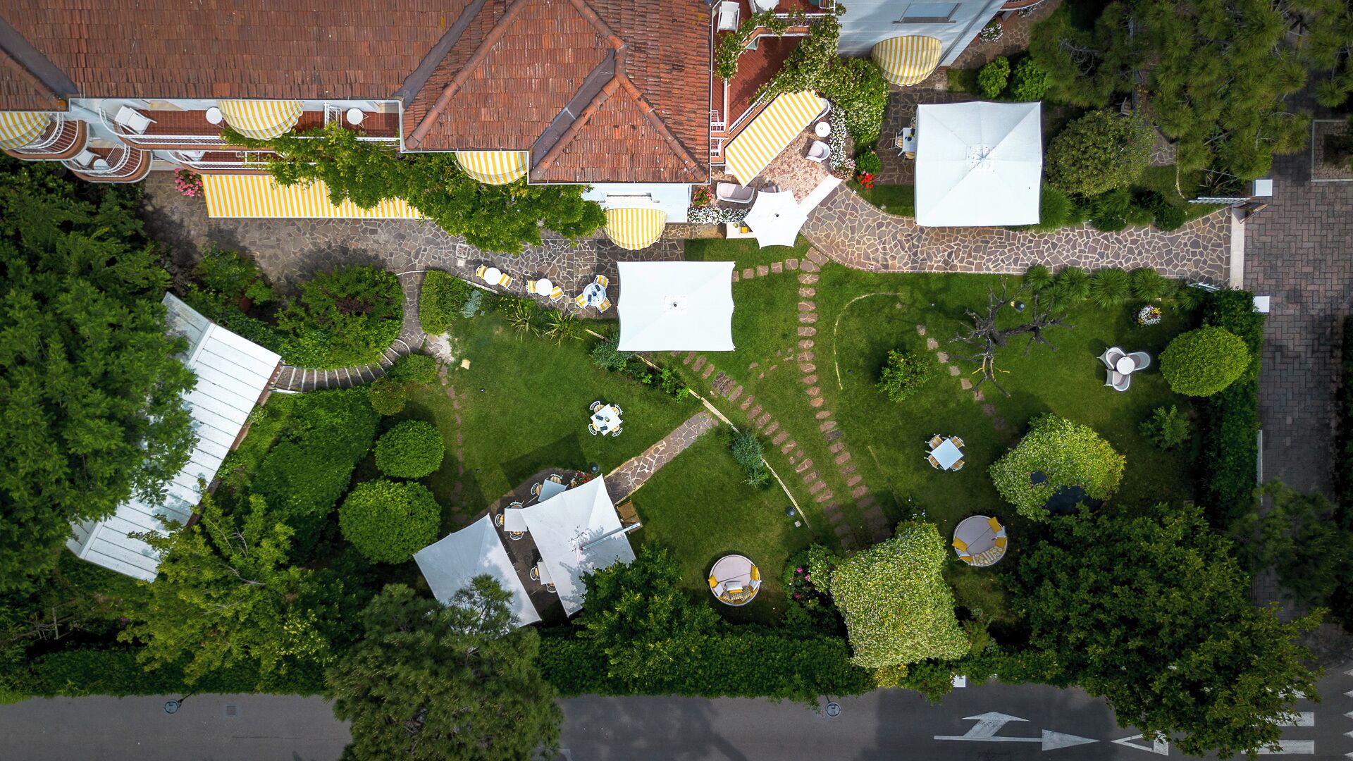 An aerial view of a property with a patio area, outdoor seating, and a garden.
