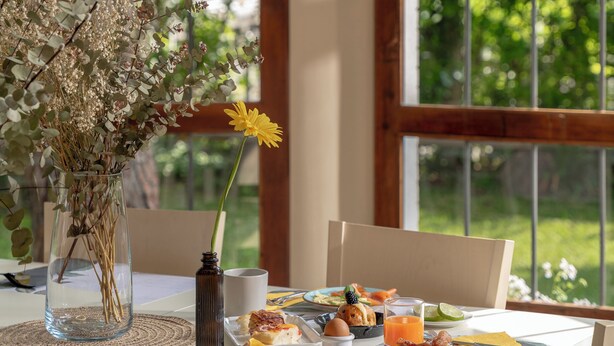 A breakfast table with a vase of dried flowers, a mug, and a plate of food. - Villa Arizona B&B (Cervia)