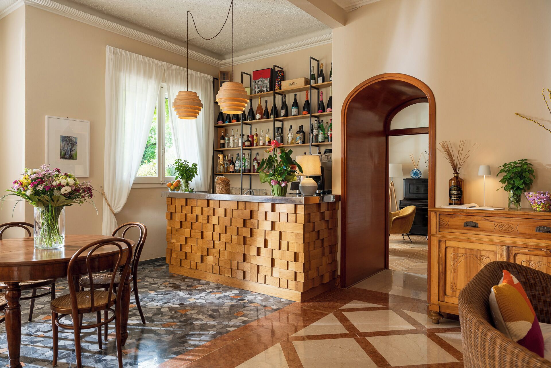 A cozy interior with a wooden bar, dining area, and a piano.