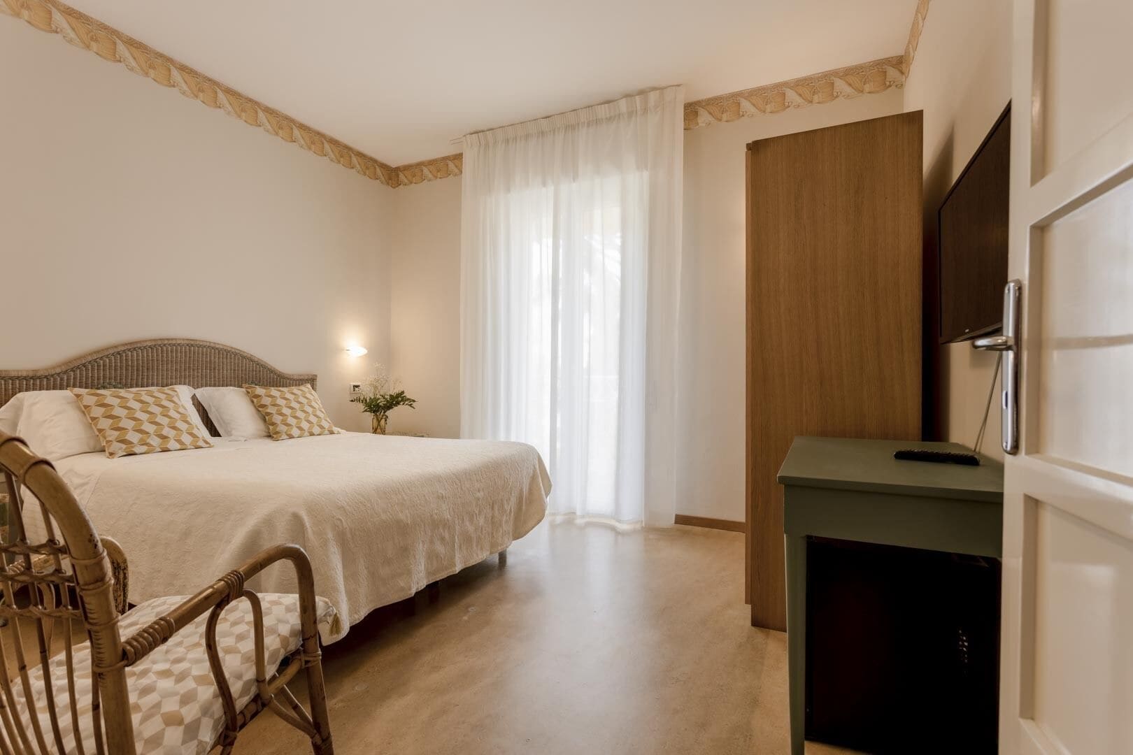 A bedroom with a bed, a chair, a desk, and a TV.