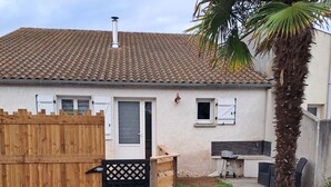 A house with a tiled roof, a wooden fence, a door, a small window, and a palm tree. - LES Sables (Yves)