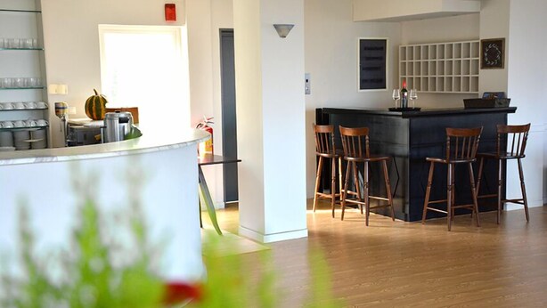 Una cocina moderna con una isla central, taburetes de bar y un comedor con sillas.