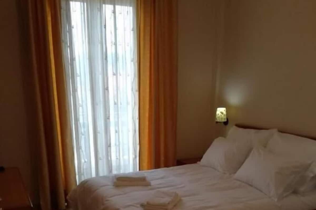 Ein Hotelzimmer mit einem Bett, einem Nachttisch und einem Fenster mit Vorhängen.