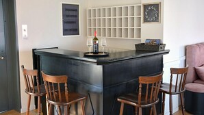 Una cocina con una isla central, cuatro sillas de madera, una botella de vino y copas.