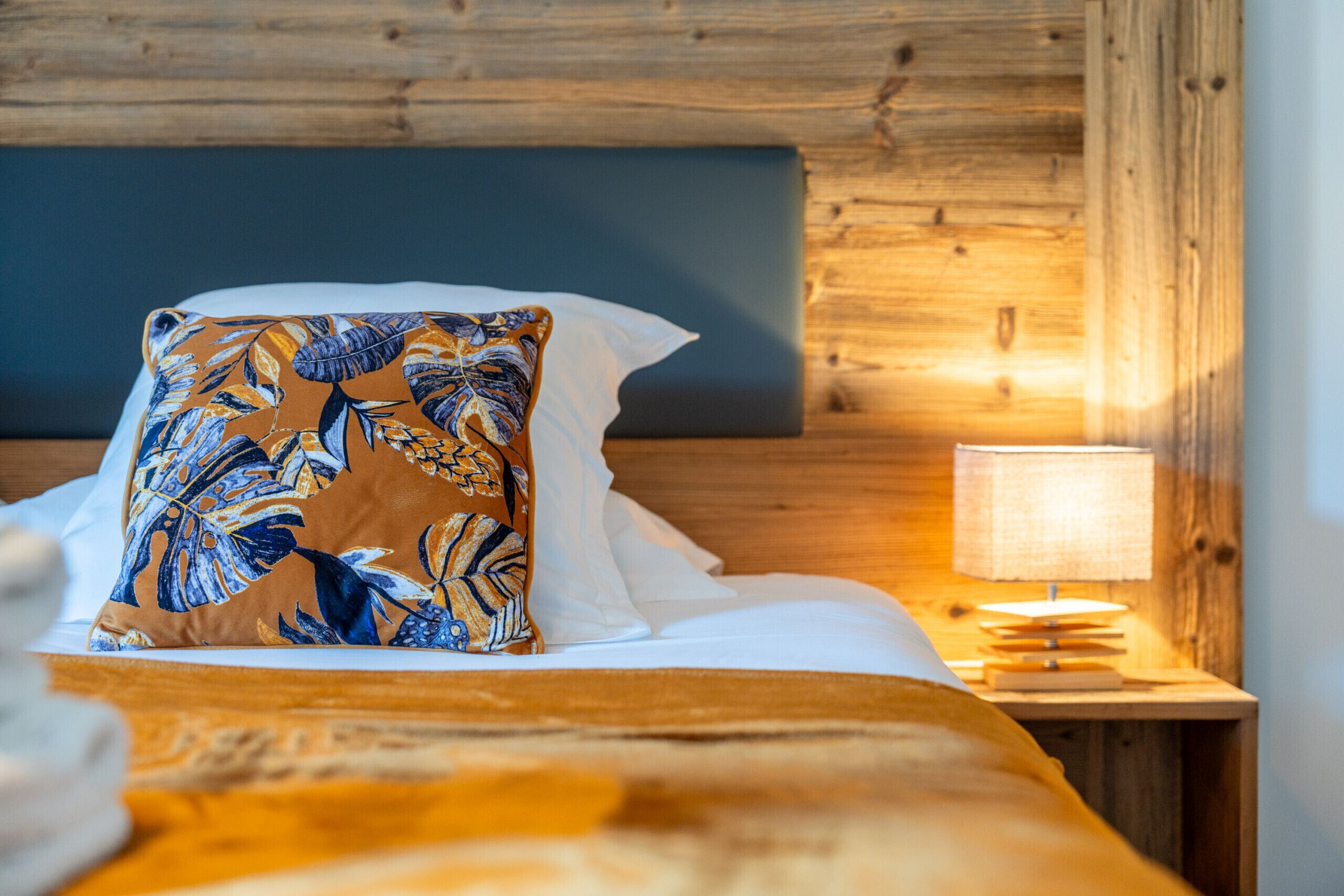 A bed with a floral pillow, a bedside lamp, and a wooden headboard.