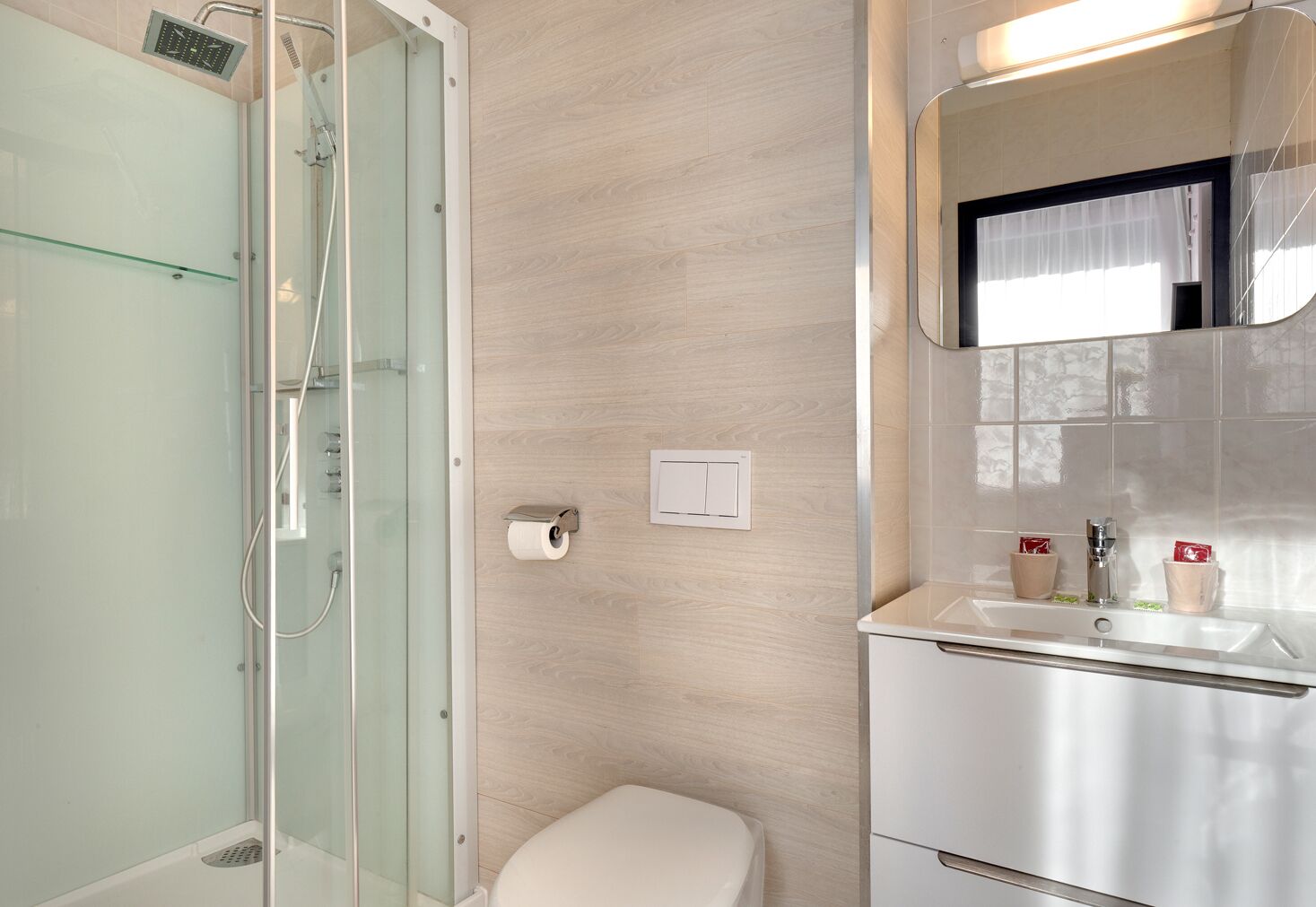 Un baño moderno con ducha de vidrio, inodoro y lavamanos con espejo.