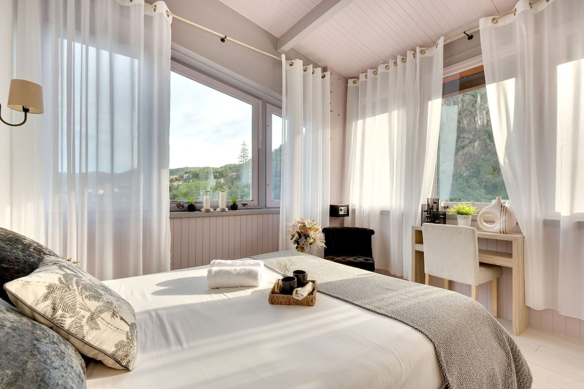 Een slaapkamer met een groot bed, een bureau en uitzicht op de omgeving.