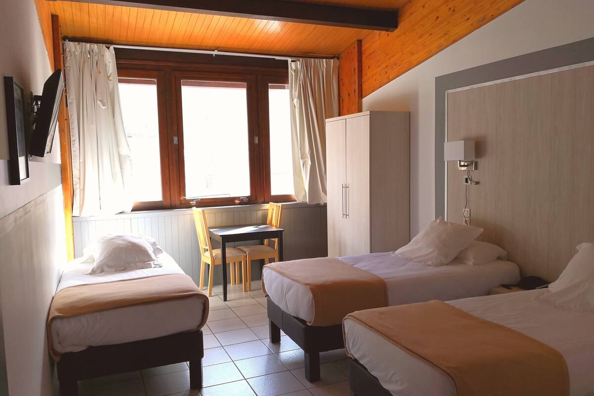 Een hotelkamer met twee eenpersoonsbedden, een bureau en een stoel.