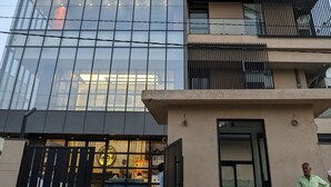 A modern building with a glass facade, multiple balconies, and a sign indicating it is a business or office building. - All Starr Sports (Jaipur)